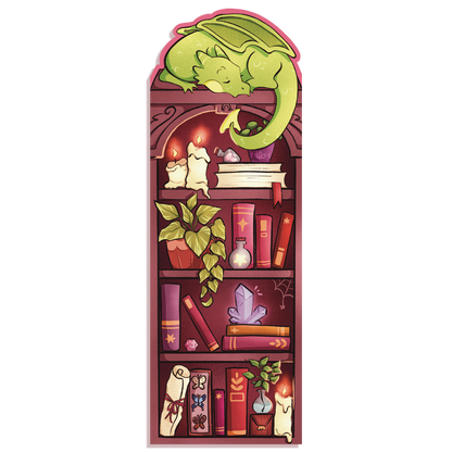A product mockup of a fantasy themed bookmark with an illustration of a green dragon sleeping on a bookshelf. The bookshelf is filled with books and magical items. 